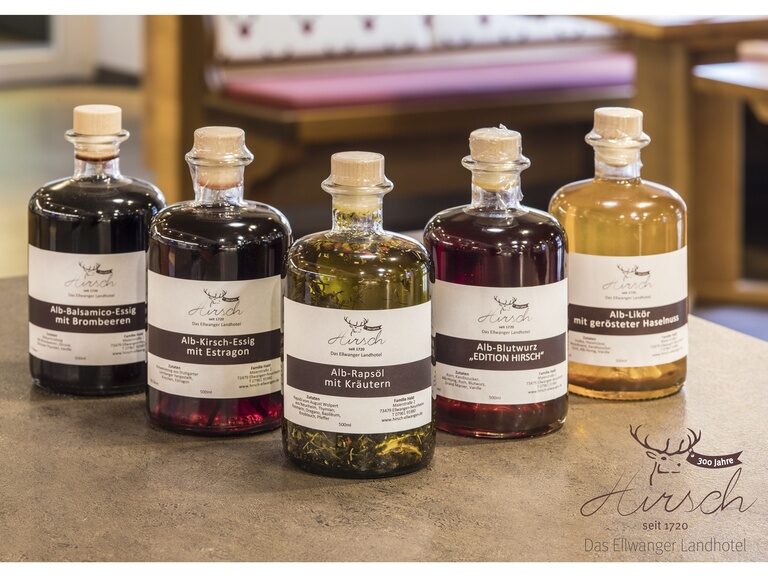 Auf einem Tisch stehen verschiedene Flaschen mit unter anderem Rapsöl, Blutwurz und Balsamico-Essig