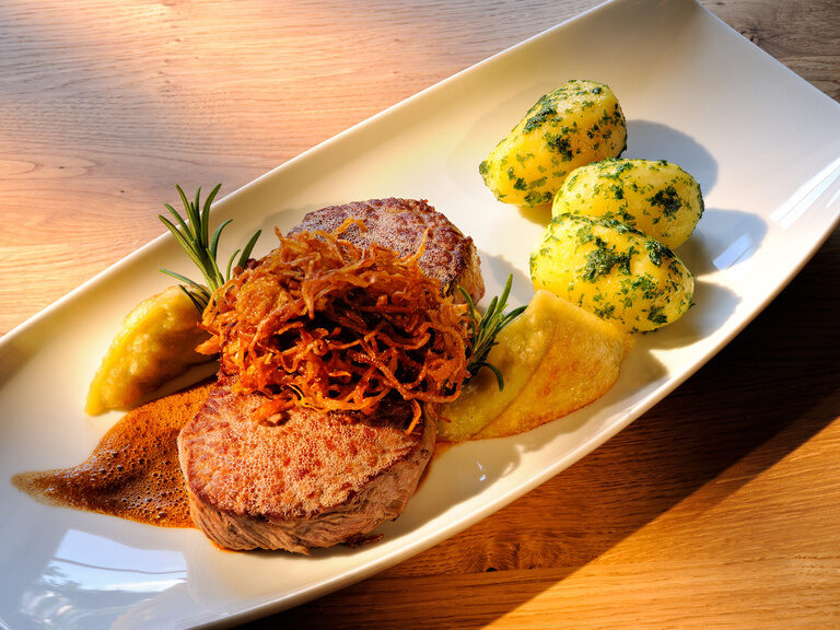 Auf einem Teller sind Kartoffeln und Fleischstücke angerichtet