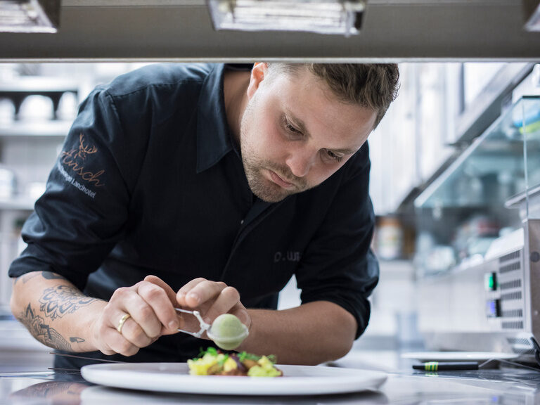 Ein Koch bereitet in einer modernen Küche einen Teller vor.