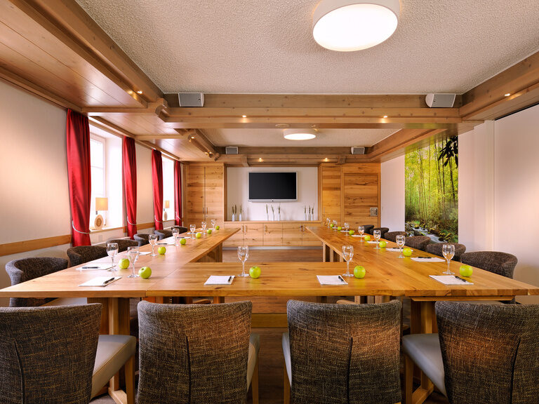 In einem großen Tagungsraum stehen Tische in U-Form für eine gelingende Besprechung