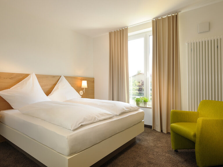 Das Comfort Zimmer bietet neben dem großen Bett unter anderem auch noch einen Sessel